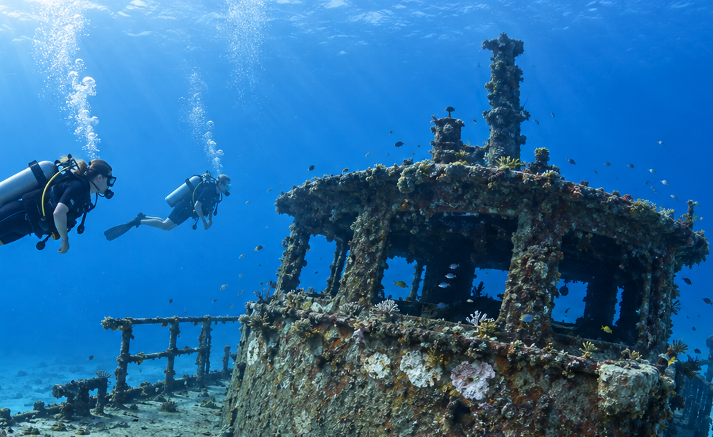 Scuba divers exploring the coral-covered Portillo wreck near Las Terrenas